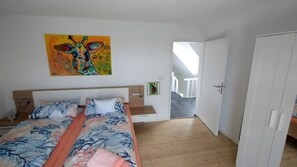 Una camera da letto con un letto, un quadro, una scala e un armadio.