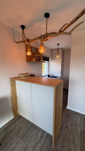 Una cocina moderna con una isla central, techo de madera decorado con adornos de asta y luces colgantes.