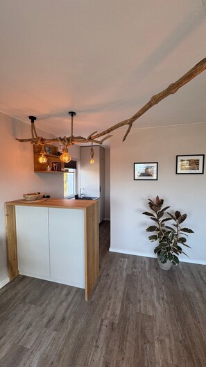 A modern kitchen with a central island, pendant lighting, and a rustic ceiling.