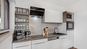 Une cuisine moderne avec des meubles blancs, un plan de travail en acier inoxydable, une machine à café et un four à micro-ondes.