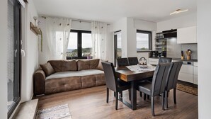 Un salon moderne comprenant un canapé, une table à manger, des chaises et un coin cuisine avec des placards et des appareils électroménagers.