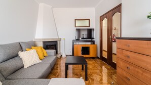 A living room with a grey sofa, wooden floor, a small table, and a wooden cabinet.
