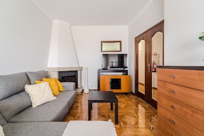 A living room with a grey sofa, wooden floor, a small table, and a wooden cabinet.
