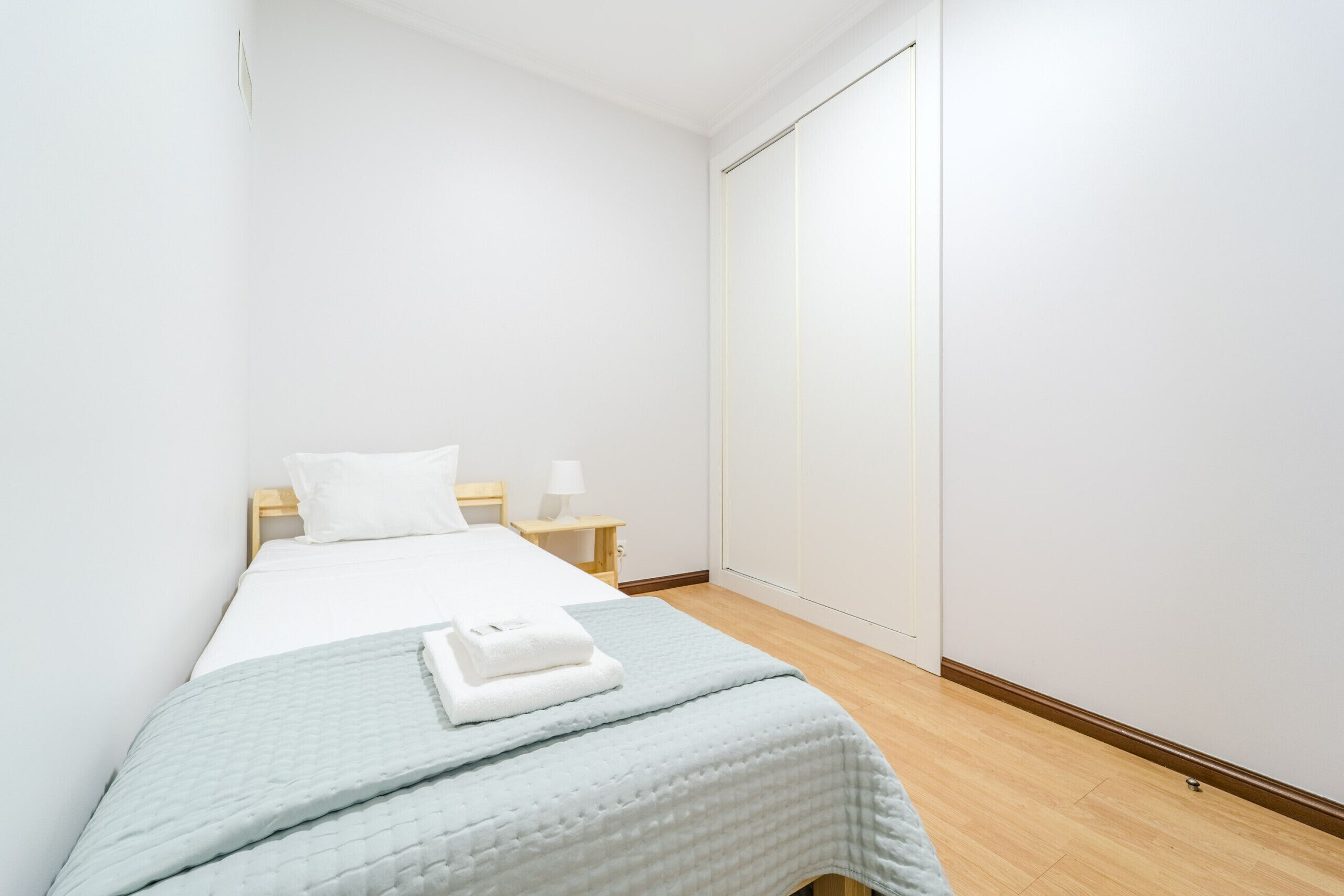 Une chambre à coucher avec un lit, une table de chevet, une lampe et une armoire.