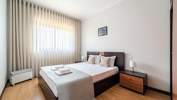 A neatly arranged hotel room with a bed, bedside table, and a radiator.