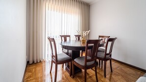 A dining area with a round table, six wooden chairs, and a vase of flowers.