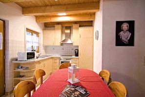 Una cocina con armarios de madera, un microondas y una mesa de comedor con sillas.