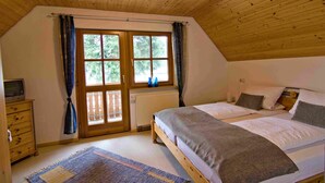 Une chambre avec un plafond en bois, un lit avec des oreillers, une commode et une fenêtre avec des rideaux.
