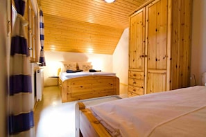 Un dormitorio con muebles de madera, una cama, un aparador y un armario.