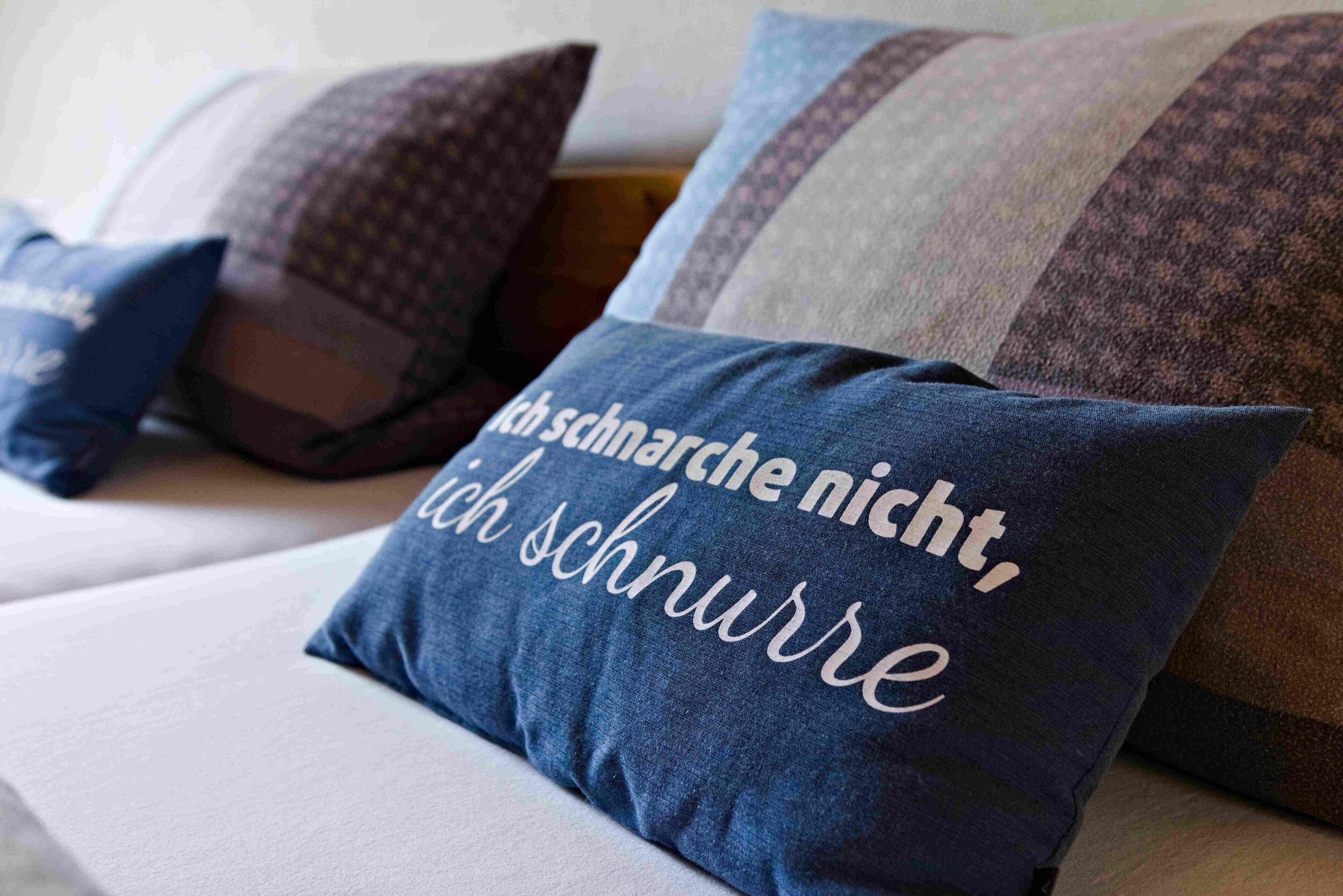 A bed with pillows, one with text in German.