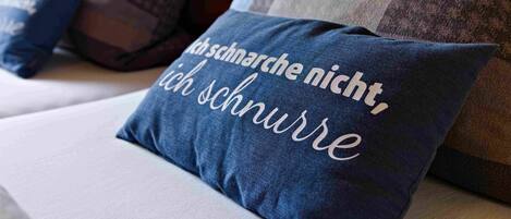 A bed with pillows, one with text in German.
