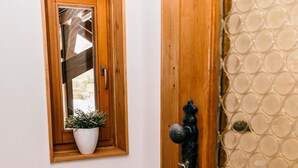 A wooden door with a glass window, a bench, and a potted plant. - Holiday Apartment 'Alte Schneiderei' with Balcony and Wi-Fi (Heideck)