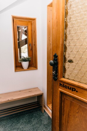 Une porte en bois avec un vitrage, un banc et une plante en pot.