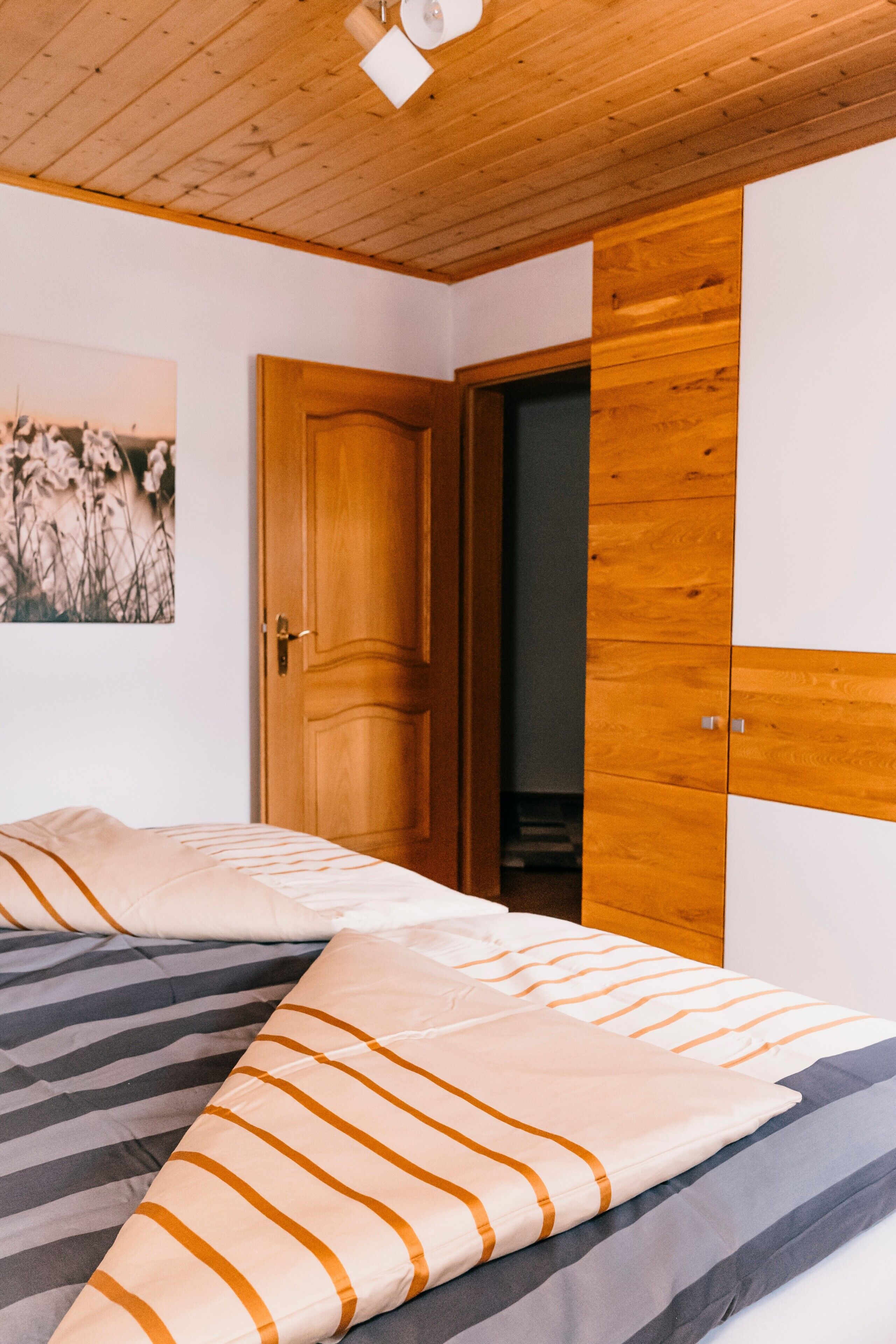 A bedroom with a bed, wooden wardrobe, and a door.