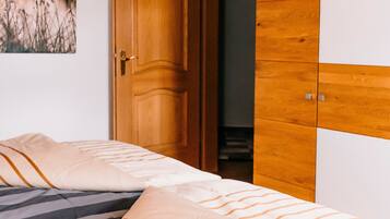 A bedroom with a bed, wooden wardrobe, and a door.