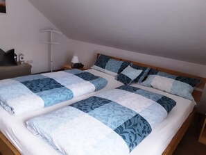 A double bed with a blue and white patterned bedspread, a bedside table with a lamp, and a wall-mounted shelf with a decorative item. - Apartment 'Schöner' with Balcony and Wi-Fi (Oberharmersbach)