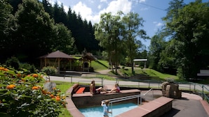 A swimming pool with a wooden deck, surrounded by greenery and a gazebo. - Apartment 'Schöner' with Balcony and Wi-Fi (Oberharmersbach)