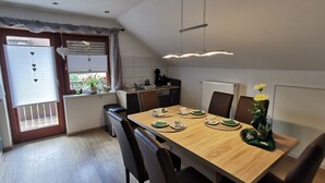 A dining area with a wooden table, chairs, and a window with blinds. - Apartment 'Schöner' with Balcony and Wi-Fi (Oberharmersbach)