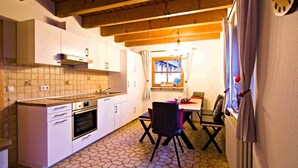 A kitchen with a tiled floor, wooden ceiling beams, and a dining area with a table and chairs. - Apartment 'Sonnenschein, 80qm' with Mountain View, Shared Garden and Wi-Fi (Seelbach)