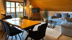 Ein gemütliches Loft mit Essbereich, einer Couch und einem Fernseher.