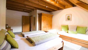 Ein Schlafzimmer mit zwei Betten, Holzbalken, einer weißen Wand und einem gerahmten Bild.