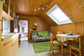 Interior de madera con cocina, comedor y un dormitorio en altillo con tragaluz.
