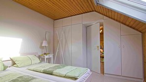 Una camera da letto con due letti, un soffitto in legno e un armadio.