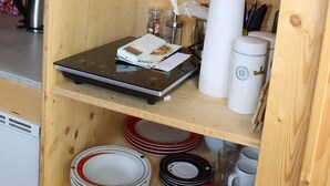 Ein Holzbodenregal mit Geschirr, einem Wasserkocher, einer Waage und einem Papierhandtuchhalter.