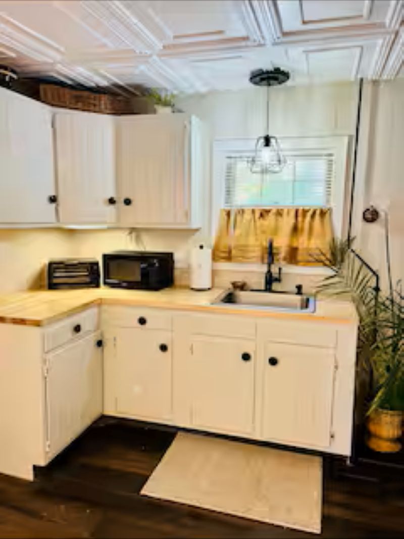 Una cocina con gabinetes blancos, un microondas y un fregadero.