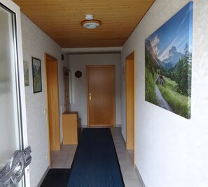 A hallway with wooden ceiling, a door, a small cabinet, and a framed picture on the wall. - Holiday Apartment 'Marina Beha' with Private Terrace, Shared Garden and Wi-Fi (Unterkirnach)