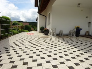 A paved patio area with a checkered pattern, outdoor sculptures, and potted plants.