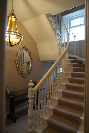 A grand staircase with ornate railings and a chandelier.