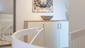 A white staircase with a white railing, leading to a room with a white cabinet and a decorative bowl on top. - Haus Belvedere - Directly behind the dune crest, only 50m to the beach crossing - (Sylt)
