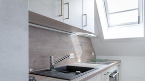 A modern kitchen with a skylight, stainless steel appliances, and light-colored cabinetry. - Haus Belvedere - Directly behind the dune crest, only 50m to the beach crossing - (Sylt)