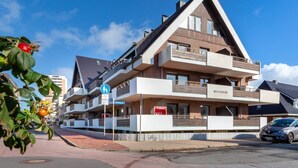 A multi-story hotel with a modern architectural design, featuring balconies and a prominent entrance. - Sea view, House Belvedere, directly behind the dune crest, for up to 5 people - (Sylt)