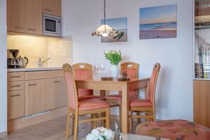 Una cocina moderna con armarios de madera, microondas y comedor con mesa dispuesta para cuatro.