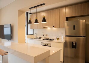 A modern kitchen with a central island, stainless steel appliances, and pendant lighting.