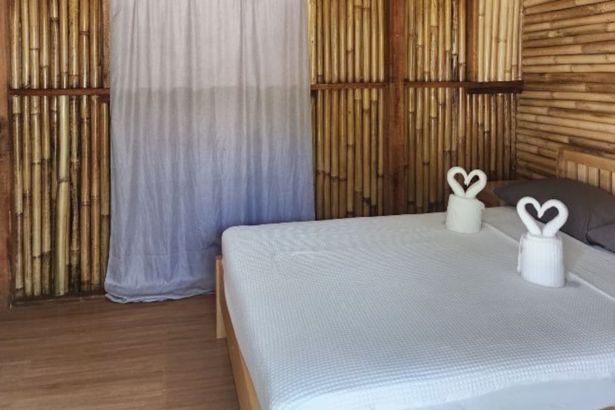 A bed with a white textured bedspread, two heart-shaped candle holders, and a wooden headboard.