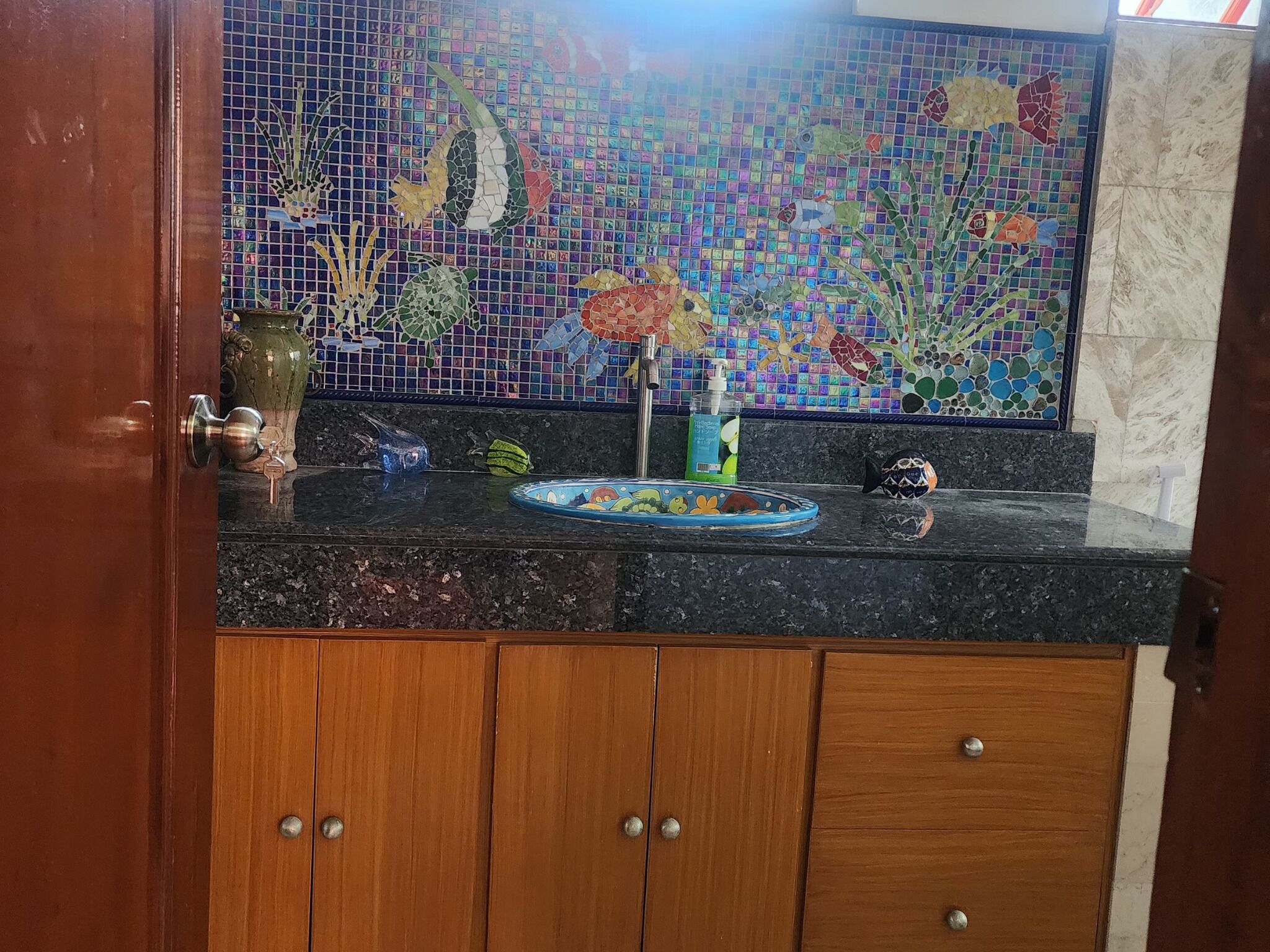 A bathroom with a mosaic tile backsplash, a sink, and wooden cabinets.