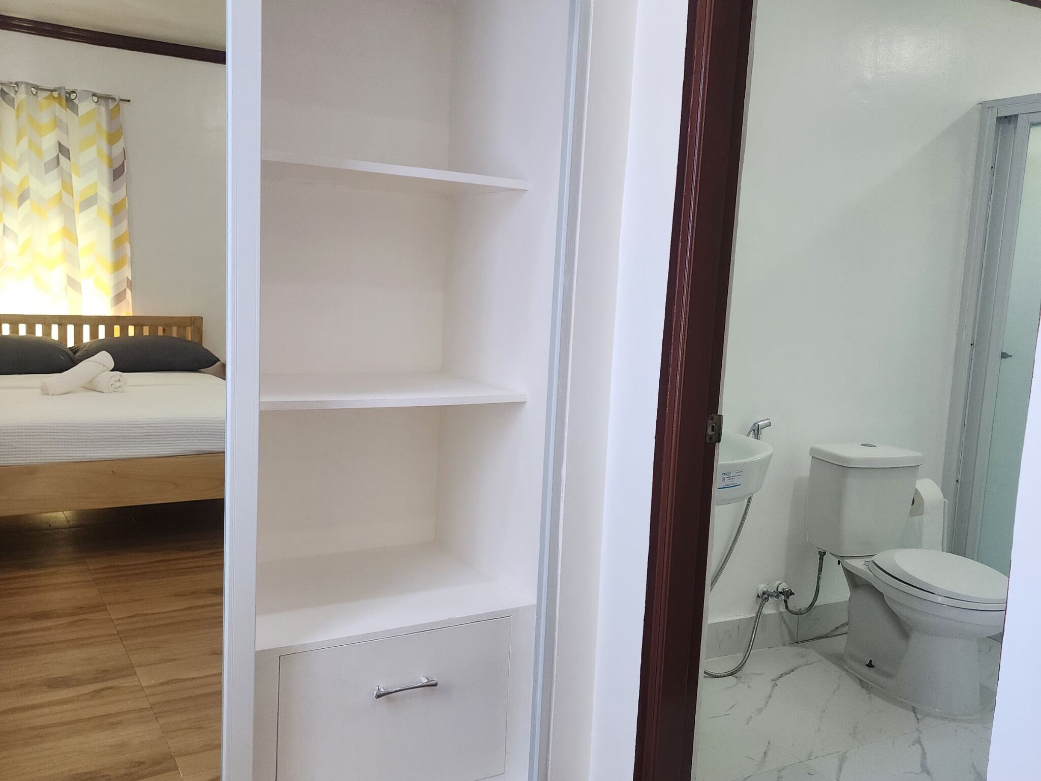 A bedroom with a bed, a wardrobe, and a bathroom with a toilet and shower.