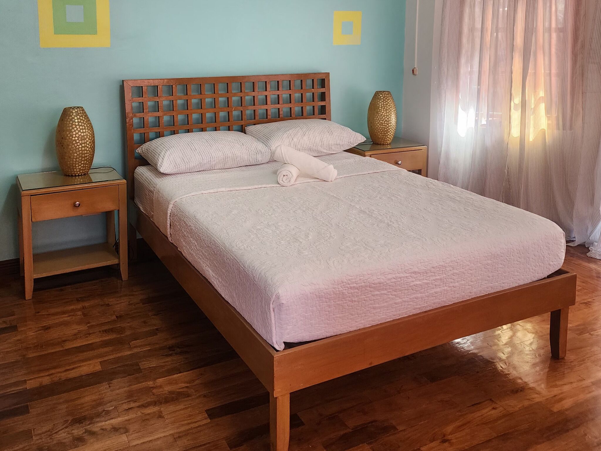 A neatly made bed with a wooden headboard, two bedside tables, and decorative vases.