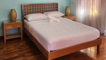 A neatly made bed with a wooden headboard, two bedside tables, and decorative vases.