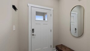A hallway with a white door, a bench, and a mirror on the wall. - Modern 16BR 16BA Condos w Garage and Patio (Wyoming)