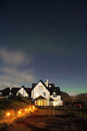 Un hilera de casas bajo un cielo nocturno despejado y estrellas visibles.