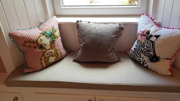 A bench with three decorative pillows.