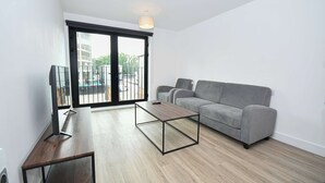 Ein modernes Wohnzimmer mit einem grauen Sofa, einem Holztisch und einem Fernseher auf einem Schrank.