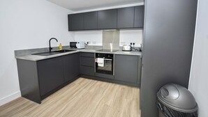 Eine moderne Küche mit dunklen Schränken, einem Edelstahl-Spülbecken und einem Einbauofen.