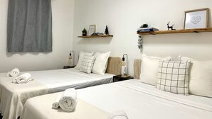 Une chambre d’hôtel avec deux lits, un rideau gris et des étagères ornées d’objets décoratifs.