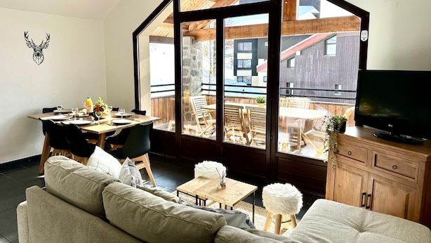 Un salon moderne doté d’une grande baie vitrée, d’un coin repas et d’un téléviseur.