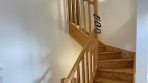 Un escalier en bois, doté d’une rampe et d’une pancarte indiquant « Salon » en haut.